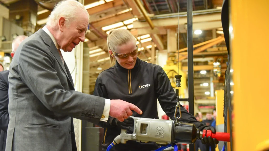 His Majesty The King helping fit a wheel to a JCB with Becky Bayliss.