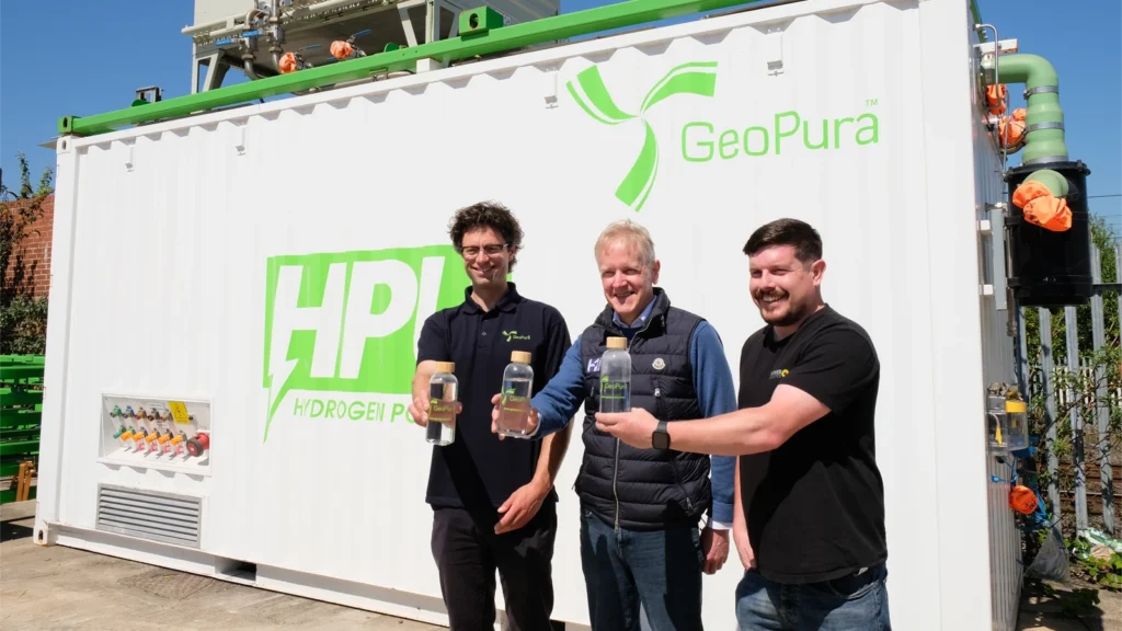 Theo Elmer, Chief Technical Officer, GeoPura, Andy Welch, Global Hydrogen Development Manager, Extreme H and Craig Hardeman, Innovation and Sustainability Development Manager, Power Logistics, hold water created as a by-product of the HPU2. (Image: Extreme H/GeoPura)