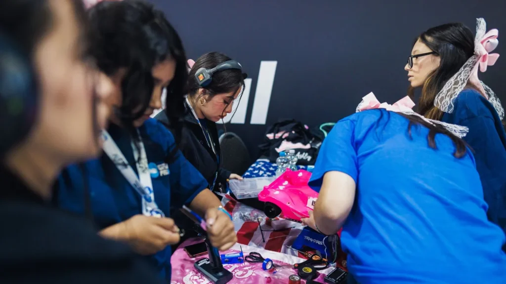 Students from an all-girls team work on a bright pink hydrogen race car during the Girls in STEM event at H2GP 2025.