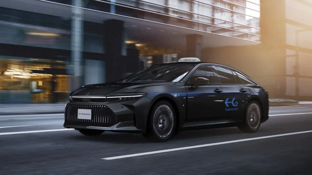 A black Toyota Crown hydrogen fuel cell taxi driving through central Tokyo with Tokyo H2 livery.
