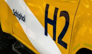 Close-up of a yellow hydrogen-powered Toyota Hilux pick-up truck marked with ‘Schiphol’ and ‘H2’ logos at Schiphol Airport.