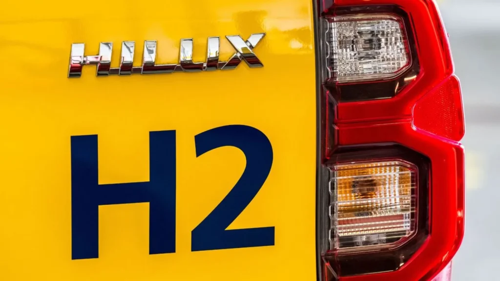 Close-up of the rear ‘HILUX’ and ‘H2’ branding on a yellow hydrogen-powered pick-up truck at Schiphol.