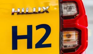 Close-up of the rear ‘HILUX’ and ‘H2’ branding on a yellow hydrogen-powered pick-up truck at Schiphol.