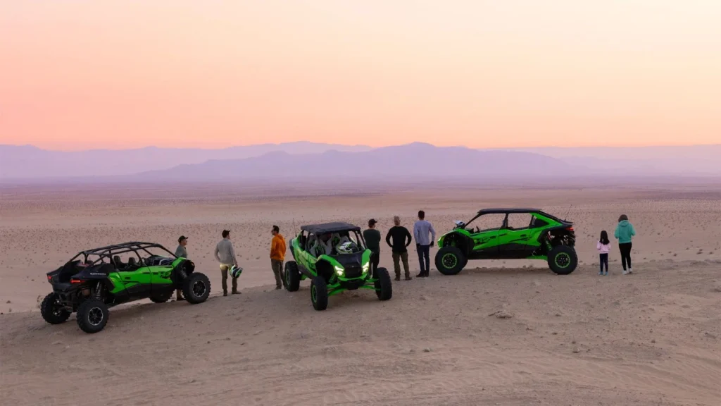 Three Kawasaki Teryx H2 hydrogen off-roaders parked at sunset overlooking desert landscape