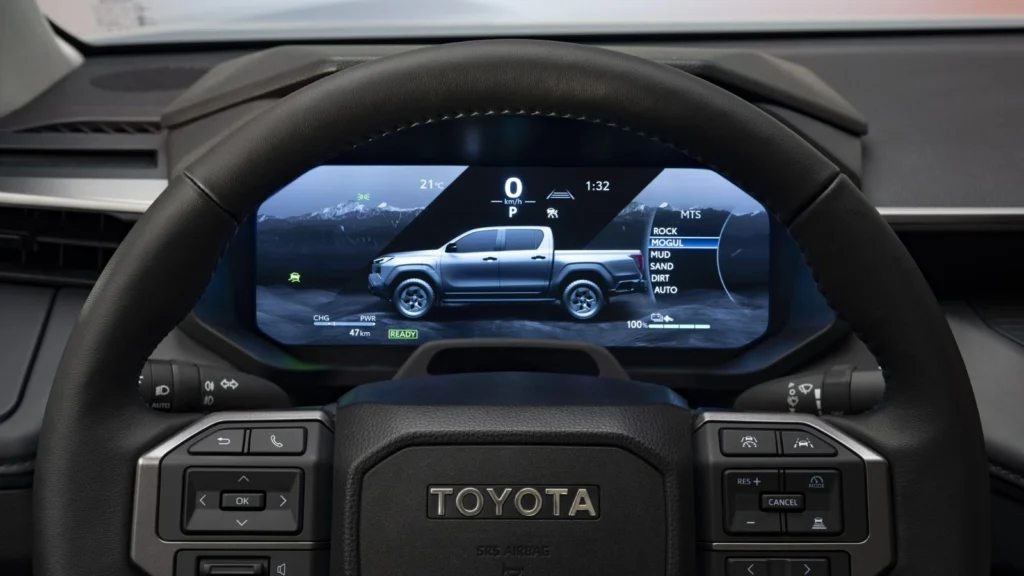 Steering wheel and digital cockpit of the Toyota Hilux BEV showing Multi-Terrain Select modes