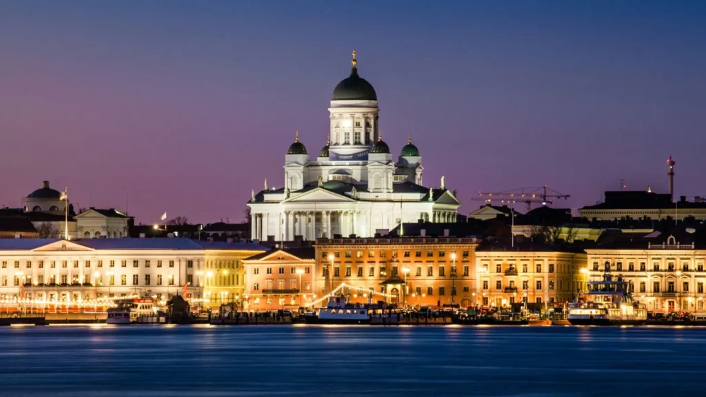 A night view of the illuminated Helsinki Cathedral and city skyline over the water, symbolizing Finland's emergence as a European leader in green hydrogen production.