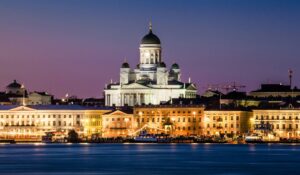 A night view of the illuminated Helsinki Cathedral and city skyline over the water, symbolizing Finland's emergence as a European leader in green hydrogen production.