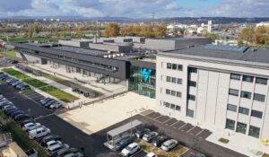 Aerial view of Symbio’s SymphonHy hydrogen fuel cell gigafactory in Saint-Fons, France, with visible solar panels, parking lots, and industrial buildings.
